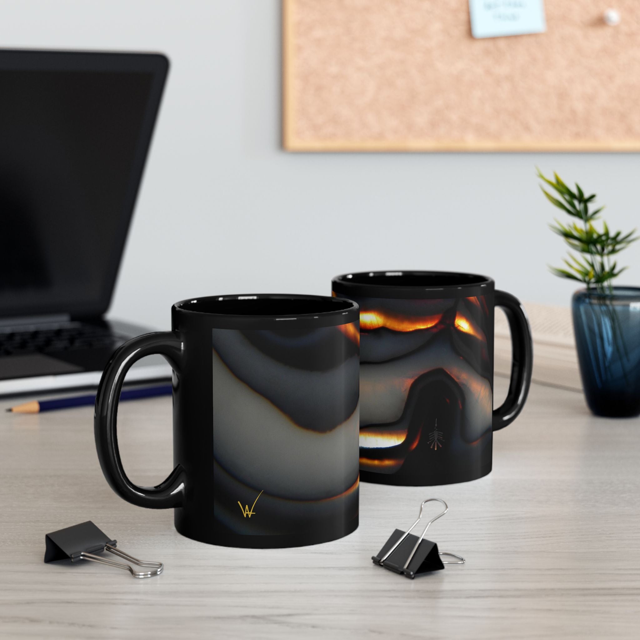 Two black mugs with a marbled design on a desk with office supplies.