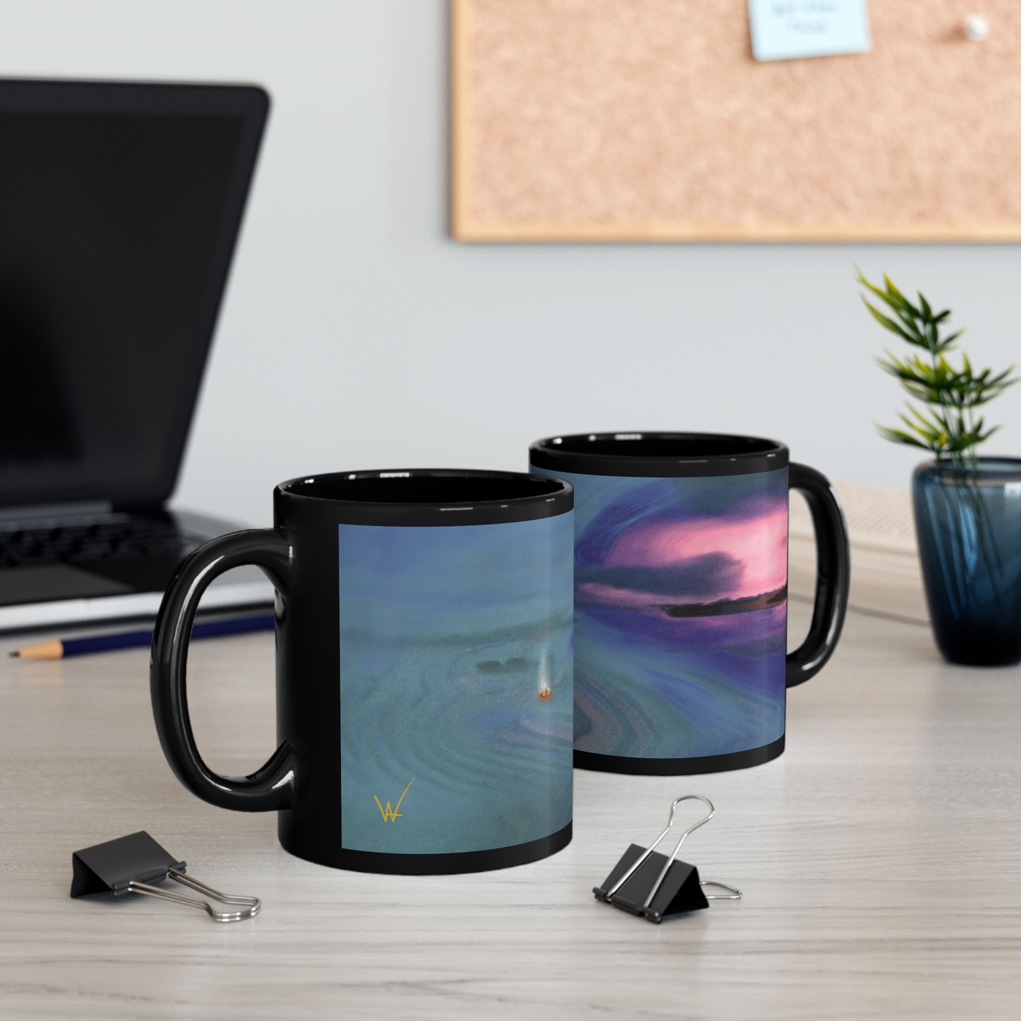 Two black mugs with scenic designs on a desk with office supplies.