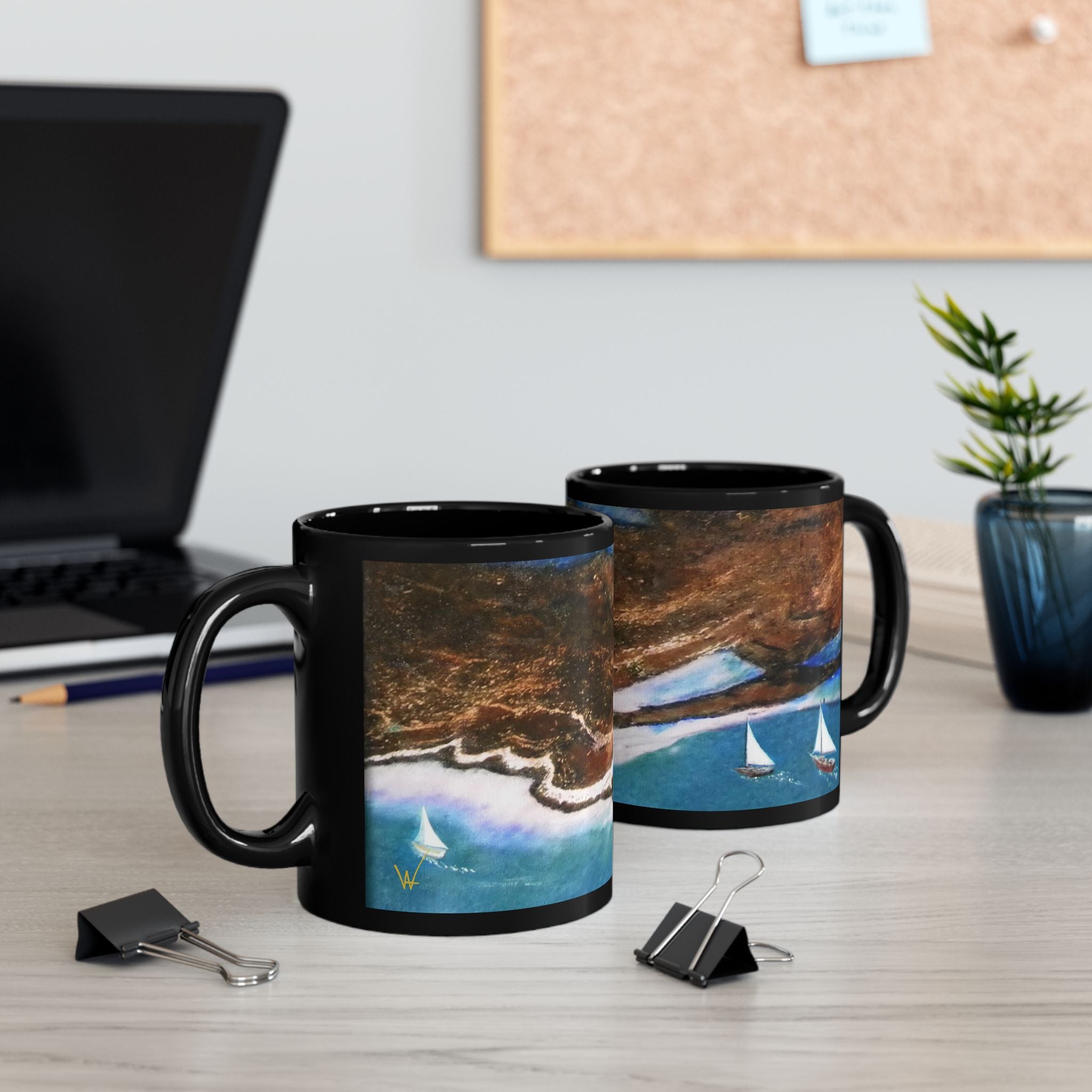 Two black mugs with scenic designs on a desk with office items.