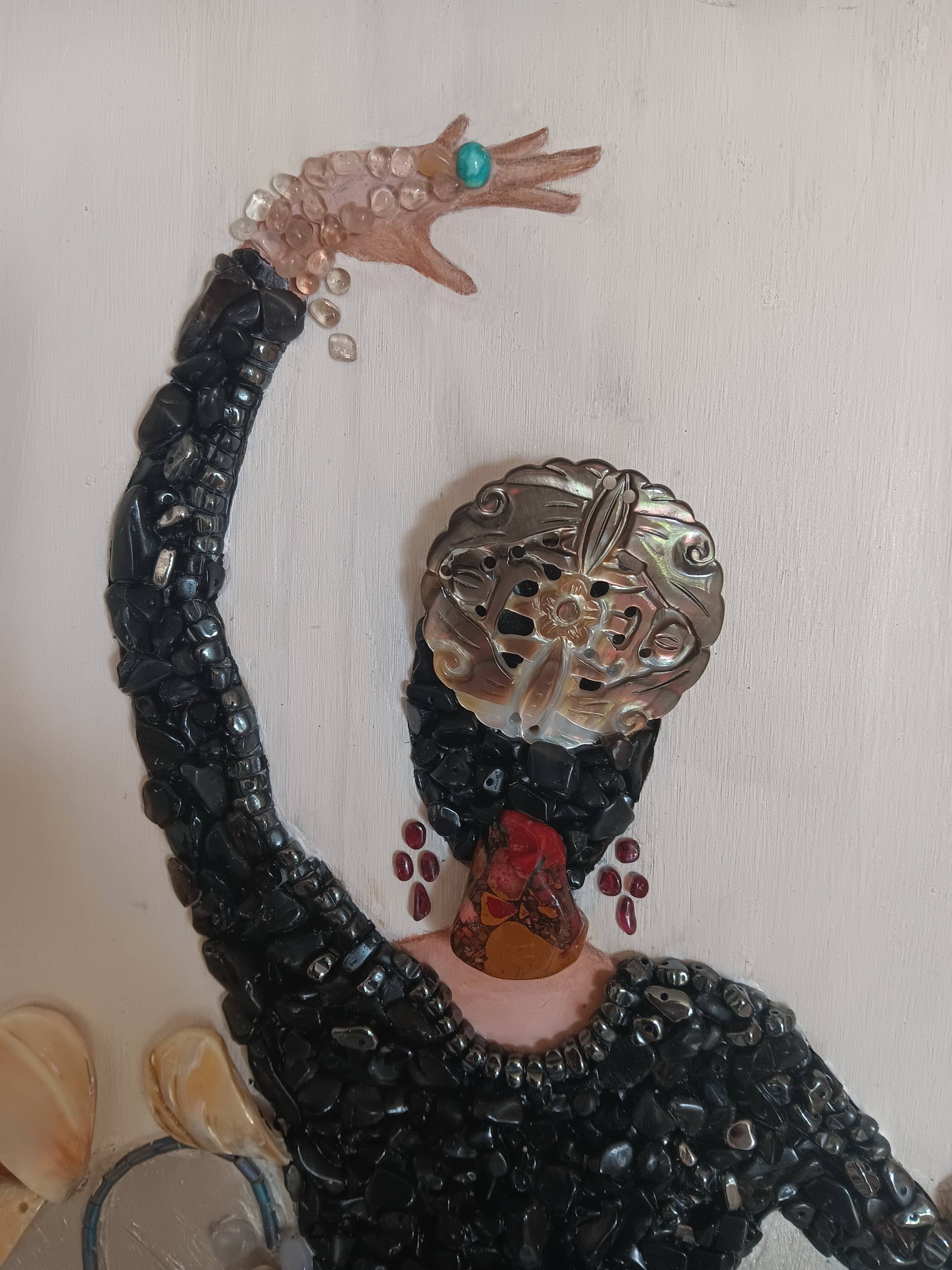 Decorative figure with intricate details and jewelry on a plain background