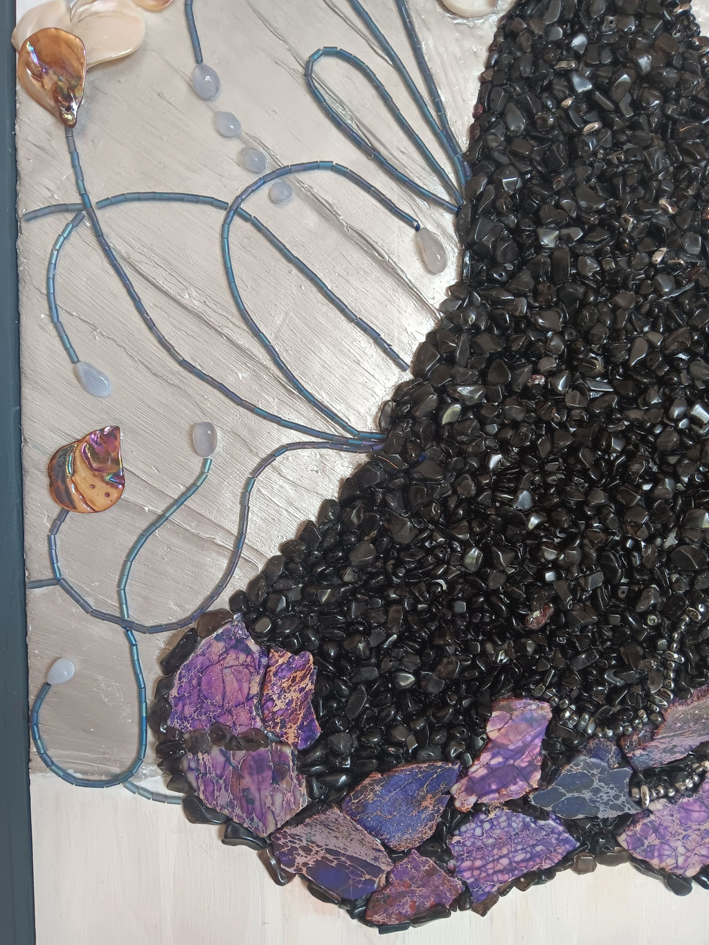Close-up of a decorative wood panel with black, purple, and blue mosaic design.
