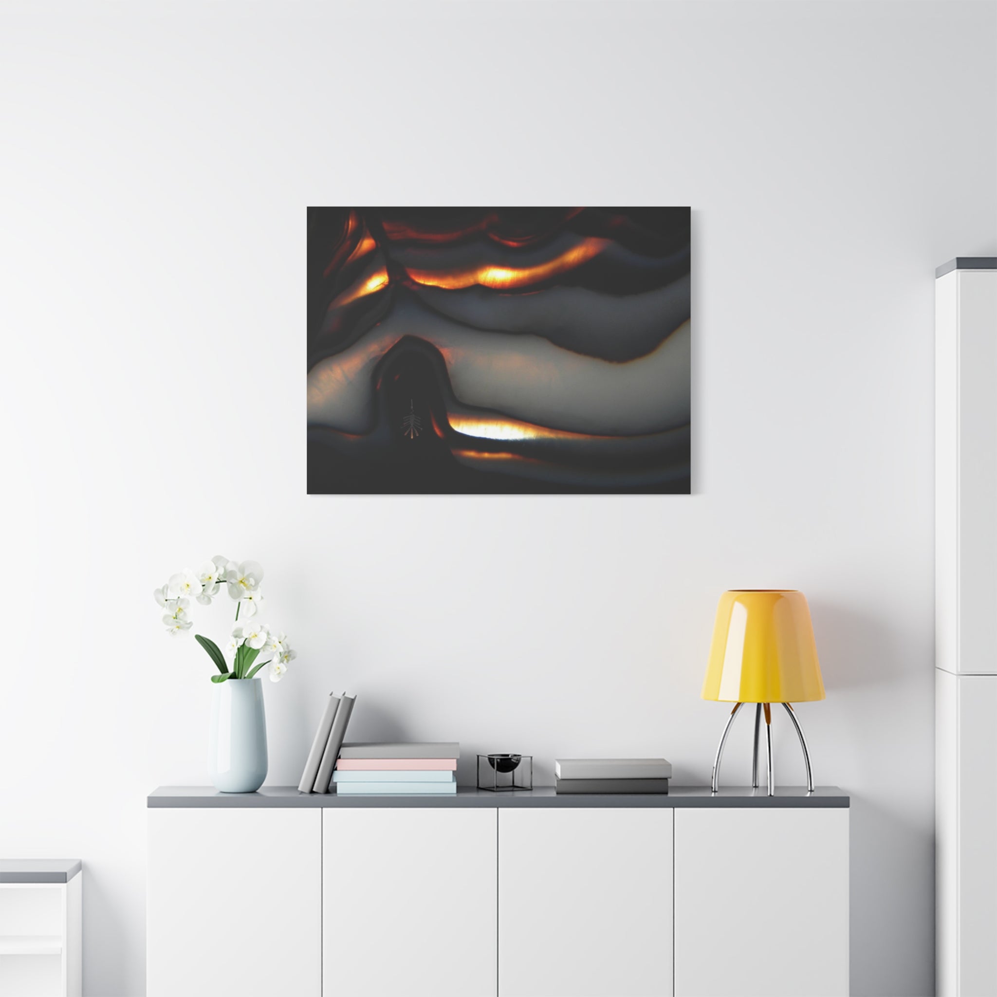 Modern interior with a painting above a white cabinet, yellow lamp, and white flowers.