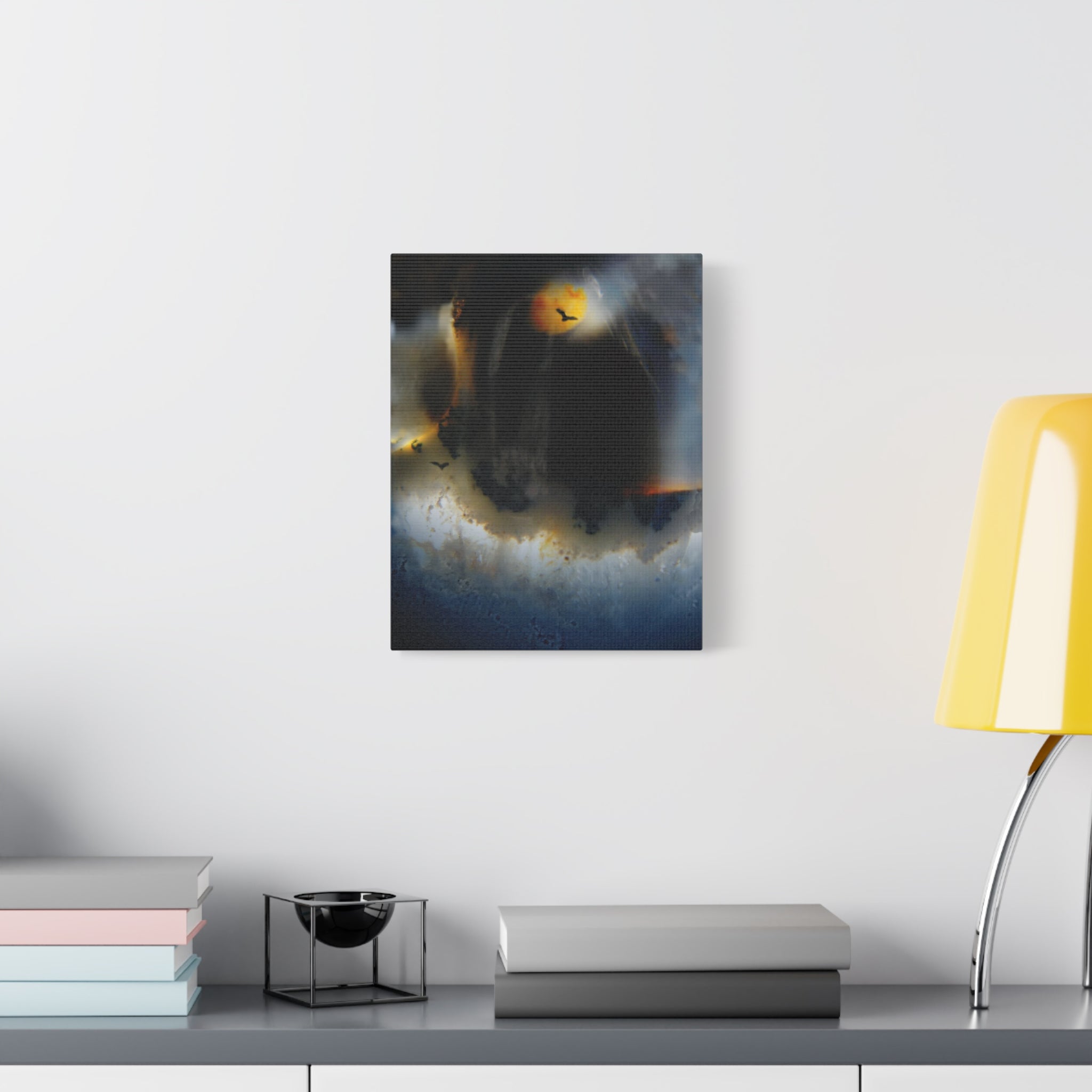 Abstract painting on a wall above a desk with books and a lamp.