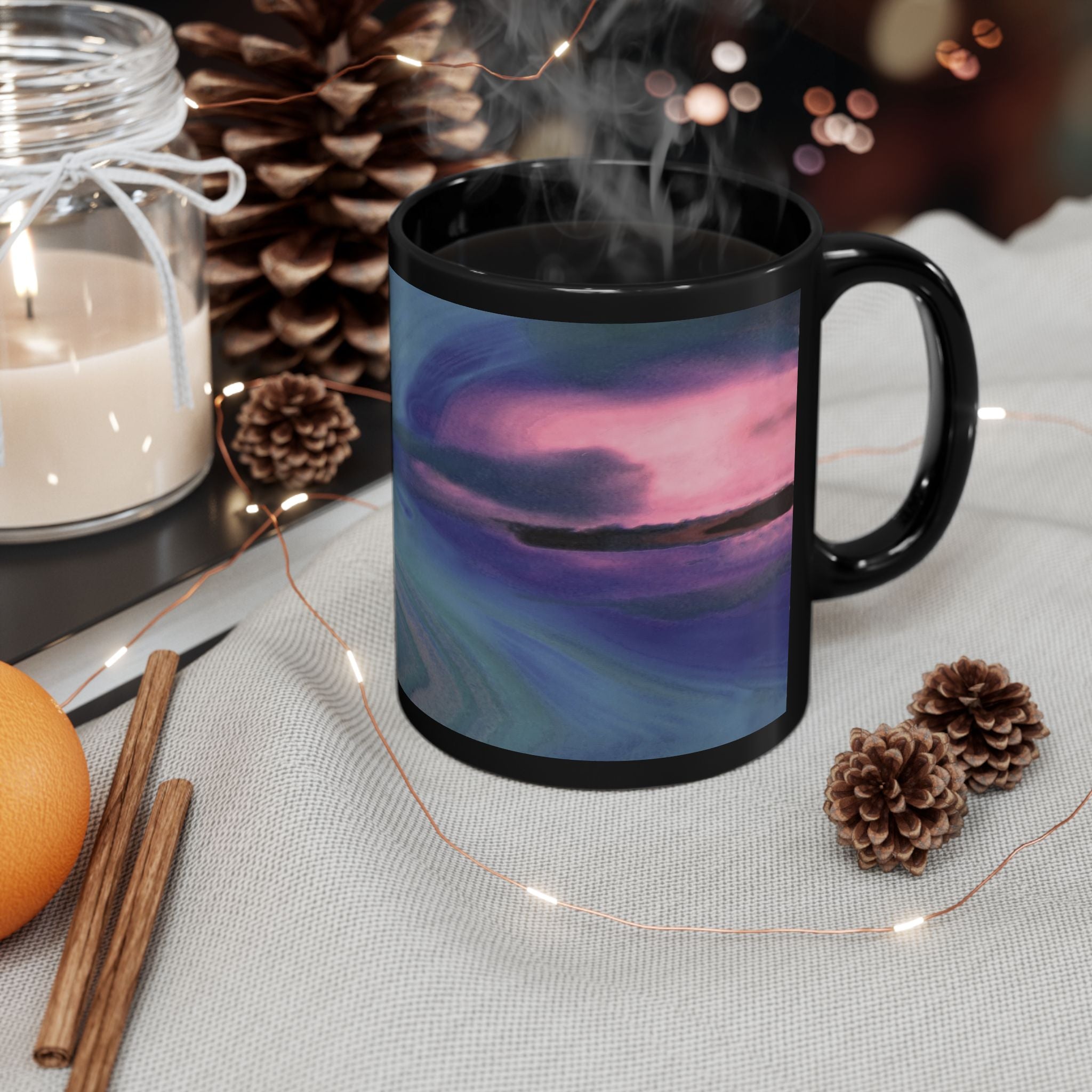 Black mug with a scenic design of a lake at sunset, surrounded by decorative items on a table.