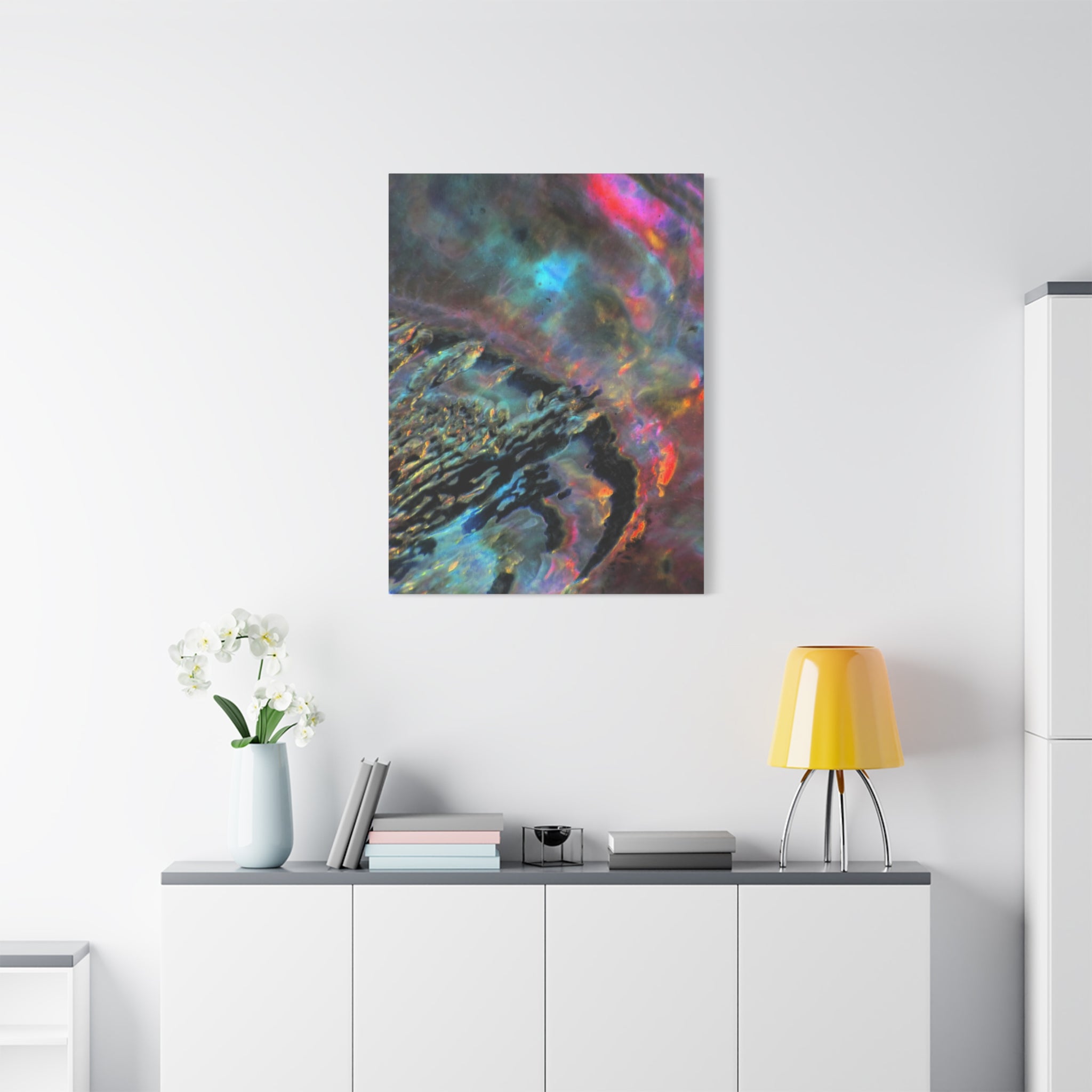 Abstract painting on a wall above a white cabinet with decorative items.