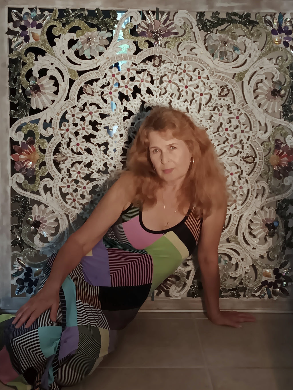 Woman posing in front of a decorative wall with intricate patterns