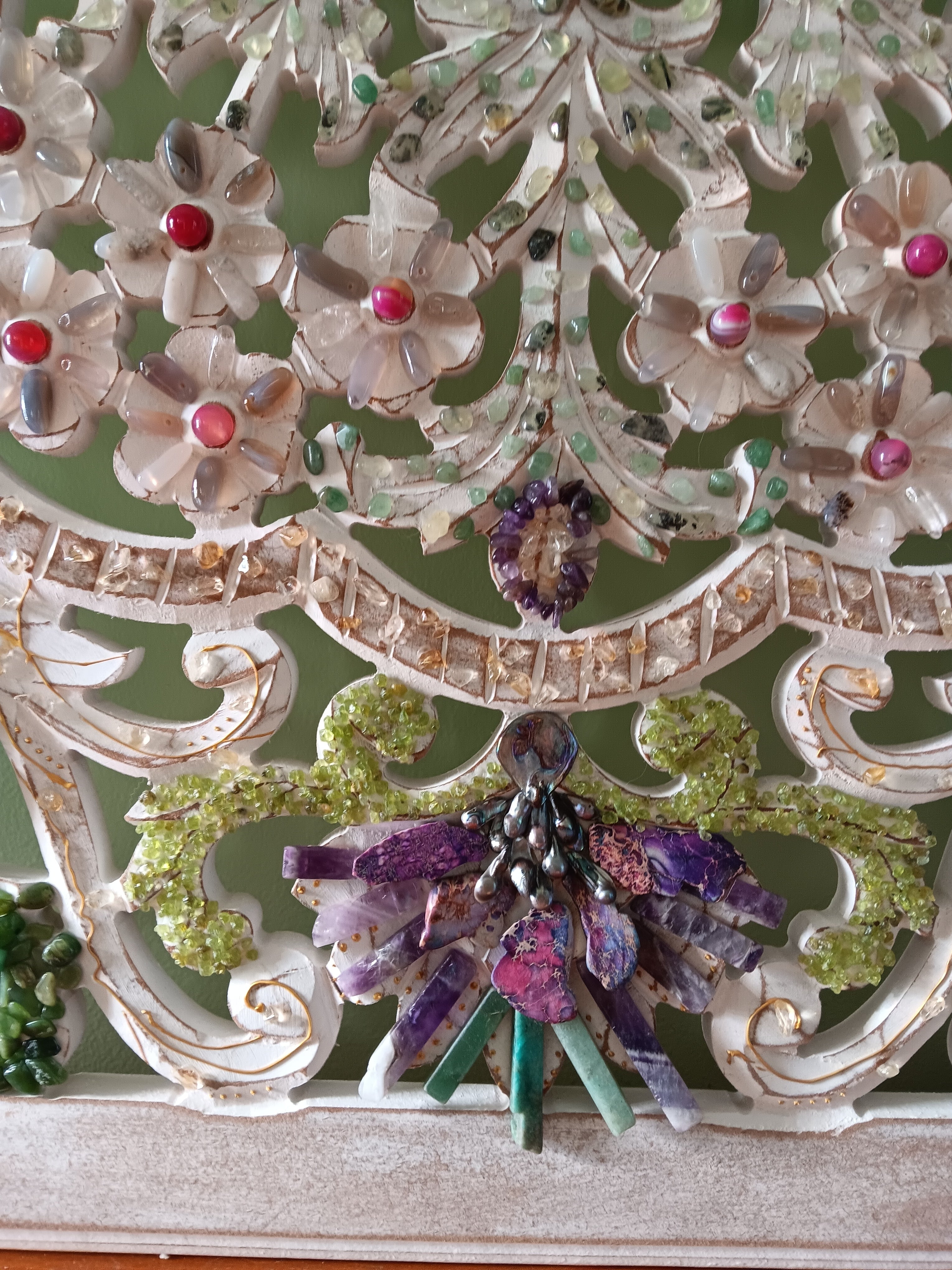 Decorative wall art with a floral design with semiprecious stones on wooden surface. 