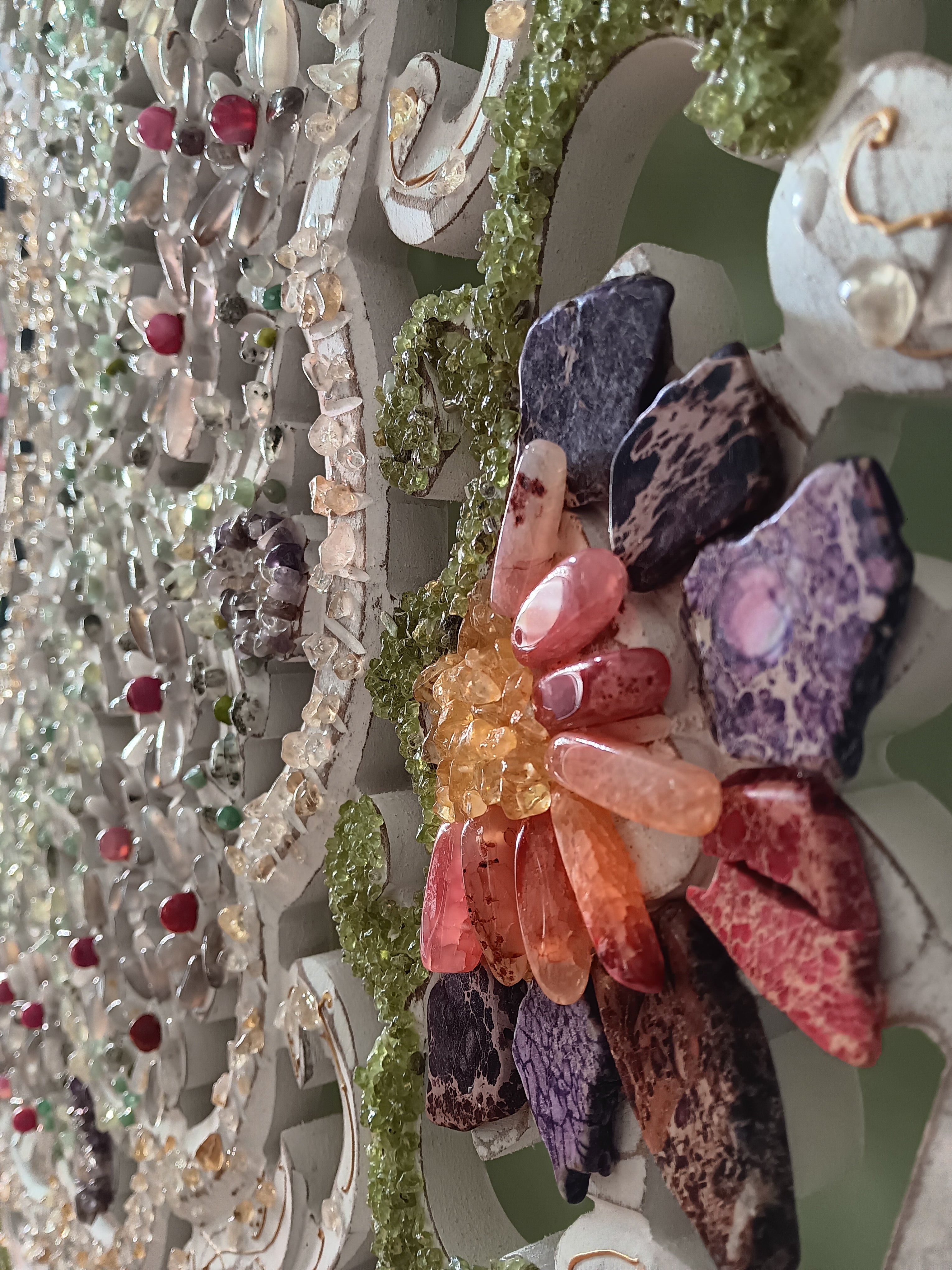 Decorative wall art with a floral design with semiprecious stones on wooden surface. 