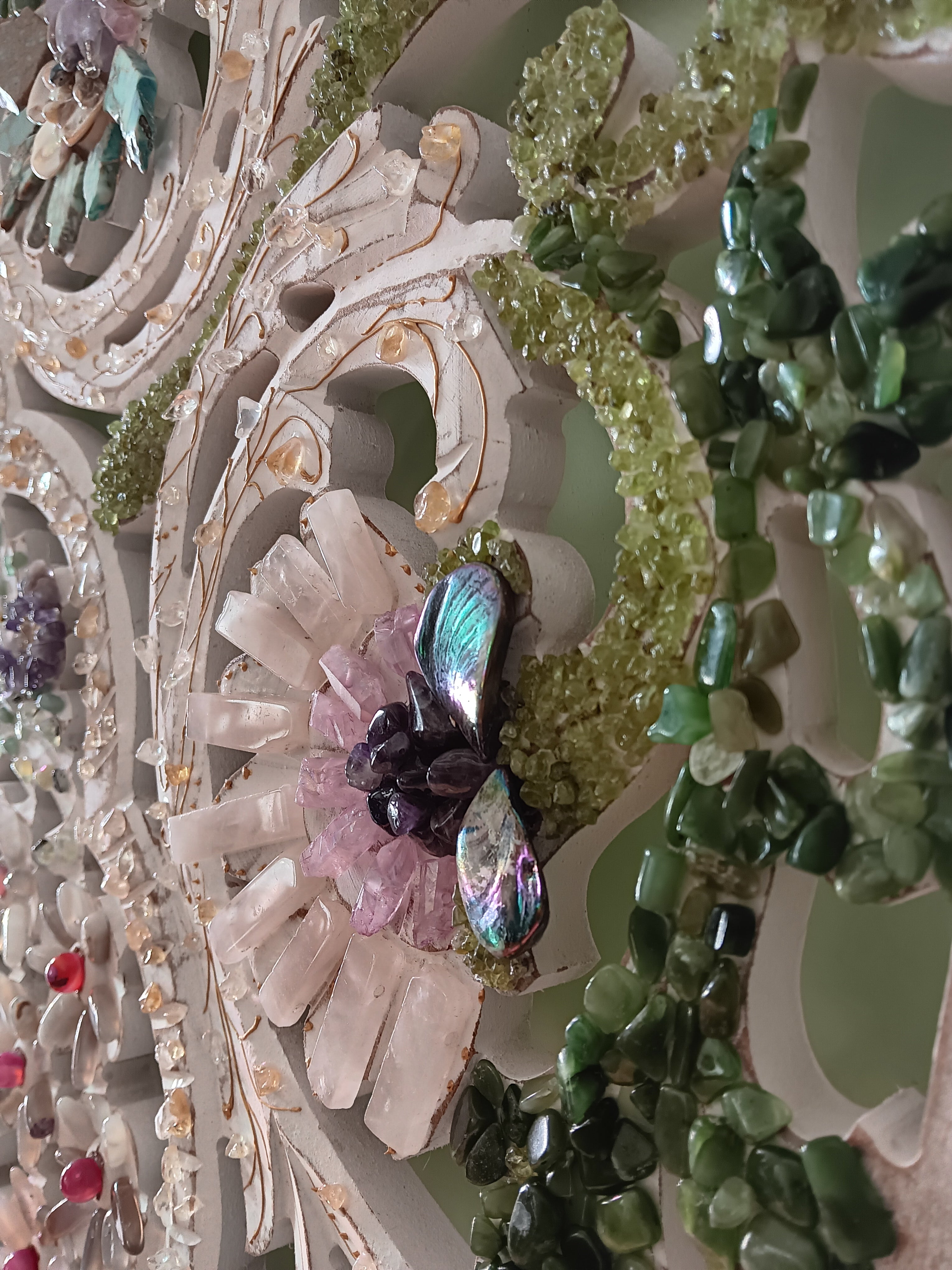 Decorative wall art with a floral design with semiprecious stones on wooden surface. 