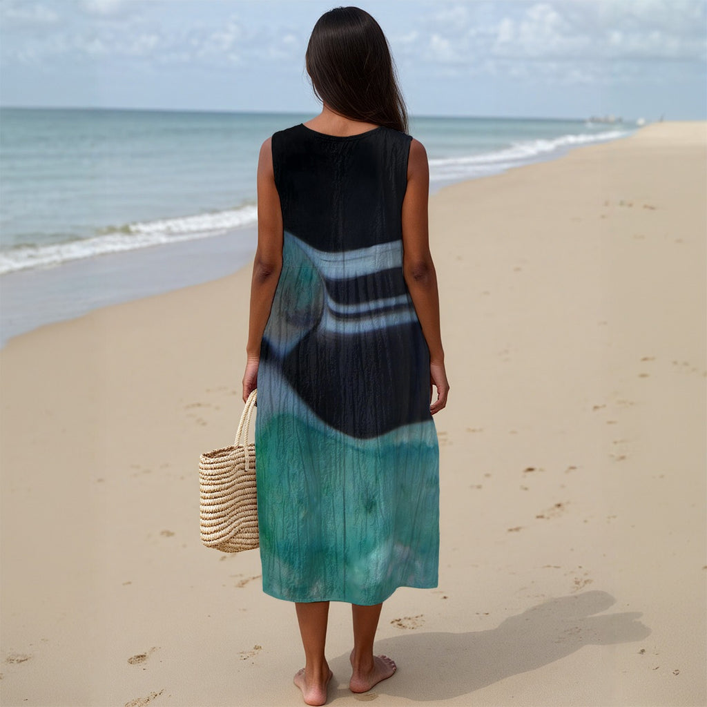 Woman in a tie-dye dress standing on a beach with ocean view