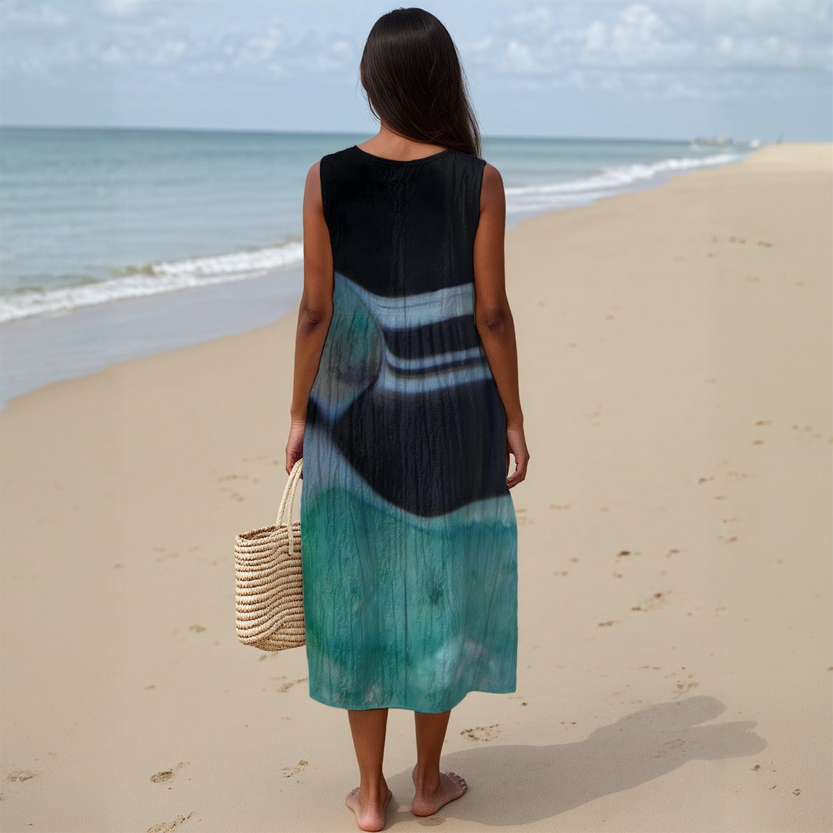 Woman in a tie-dye dress standing on a beach with ocean view