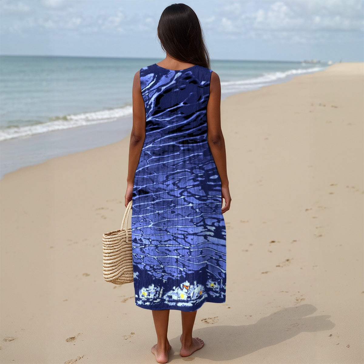 Woman in a blue dress standing on a beach with ocean view