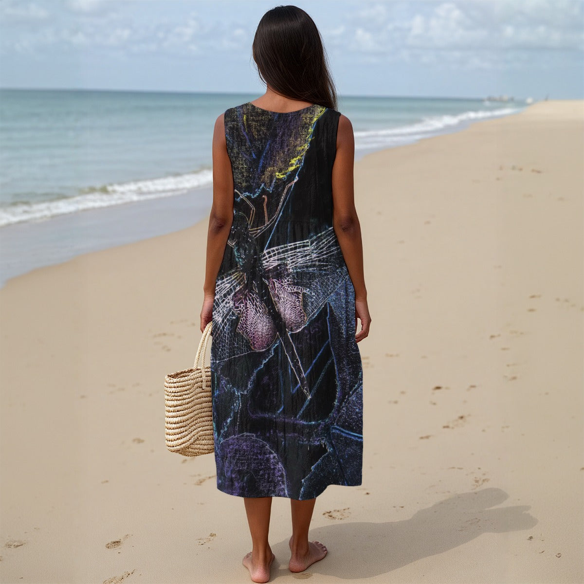 Woman in a patterned dress standing on a beach with ocean view