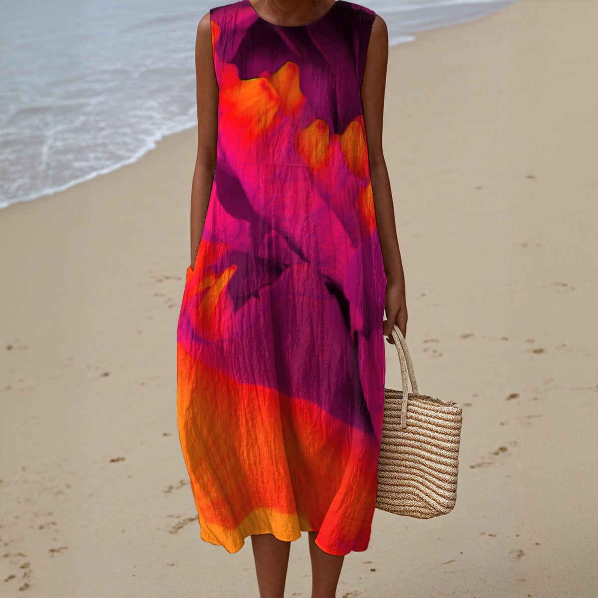 Person wearing a colorful dress on a beach holding a woven bag.