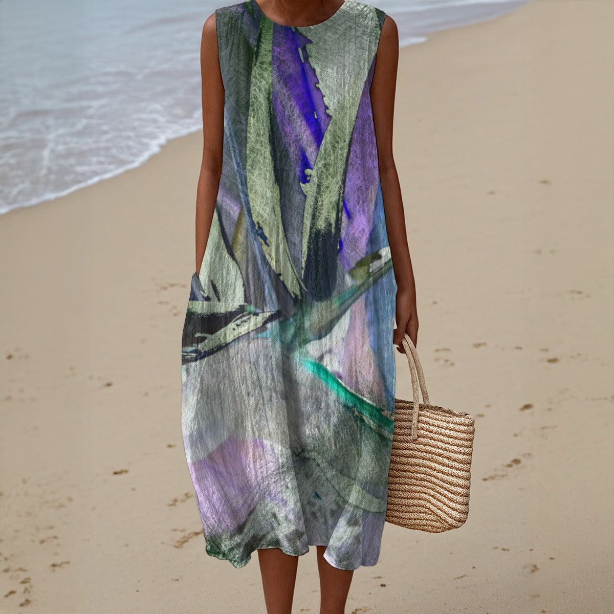 Person wearing a sleeveless, multicolored dress on a beach holding a woven bag.