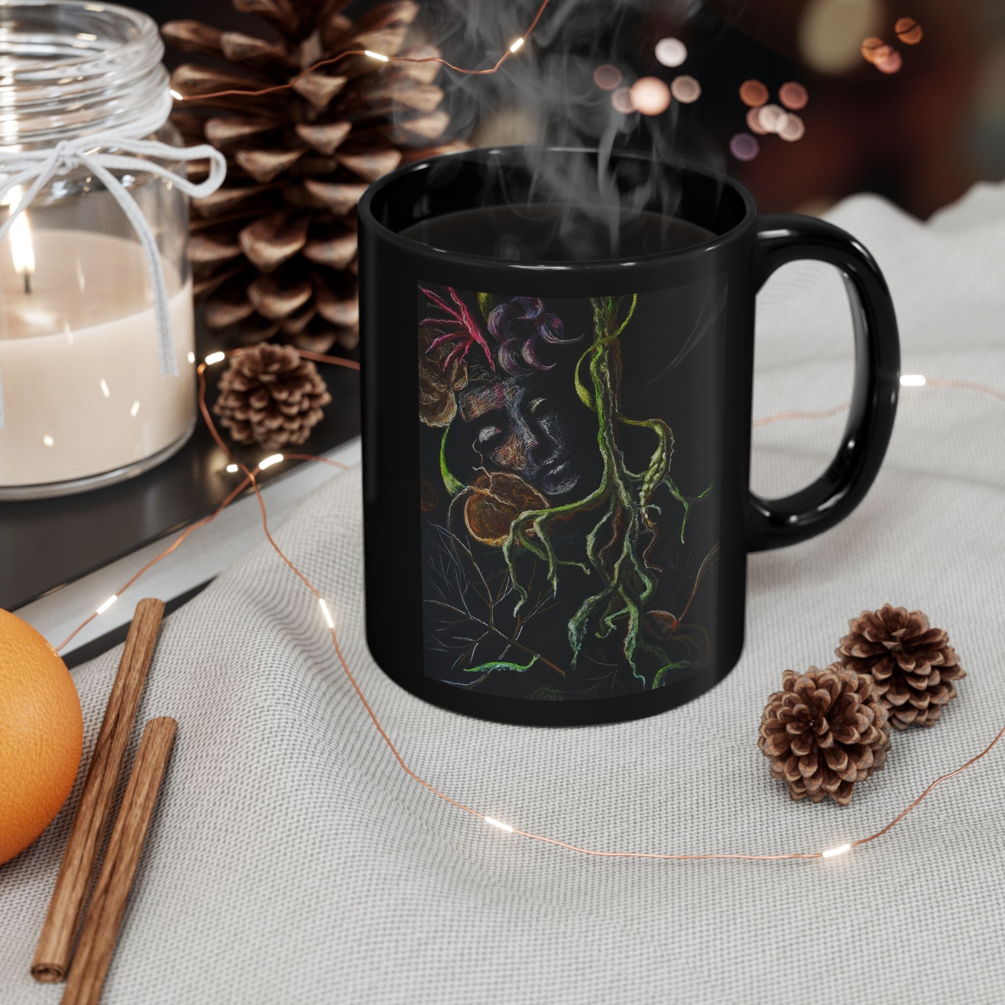 Black mug with decorative design on a table with candles, oranges, and pinecones.