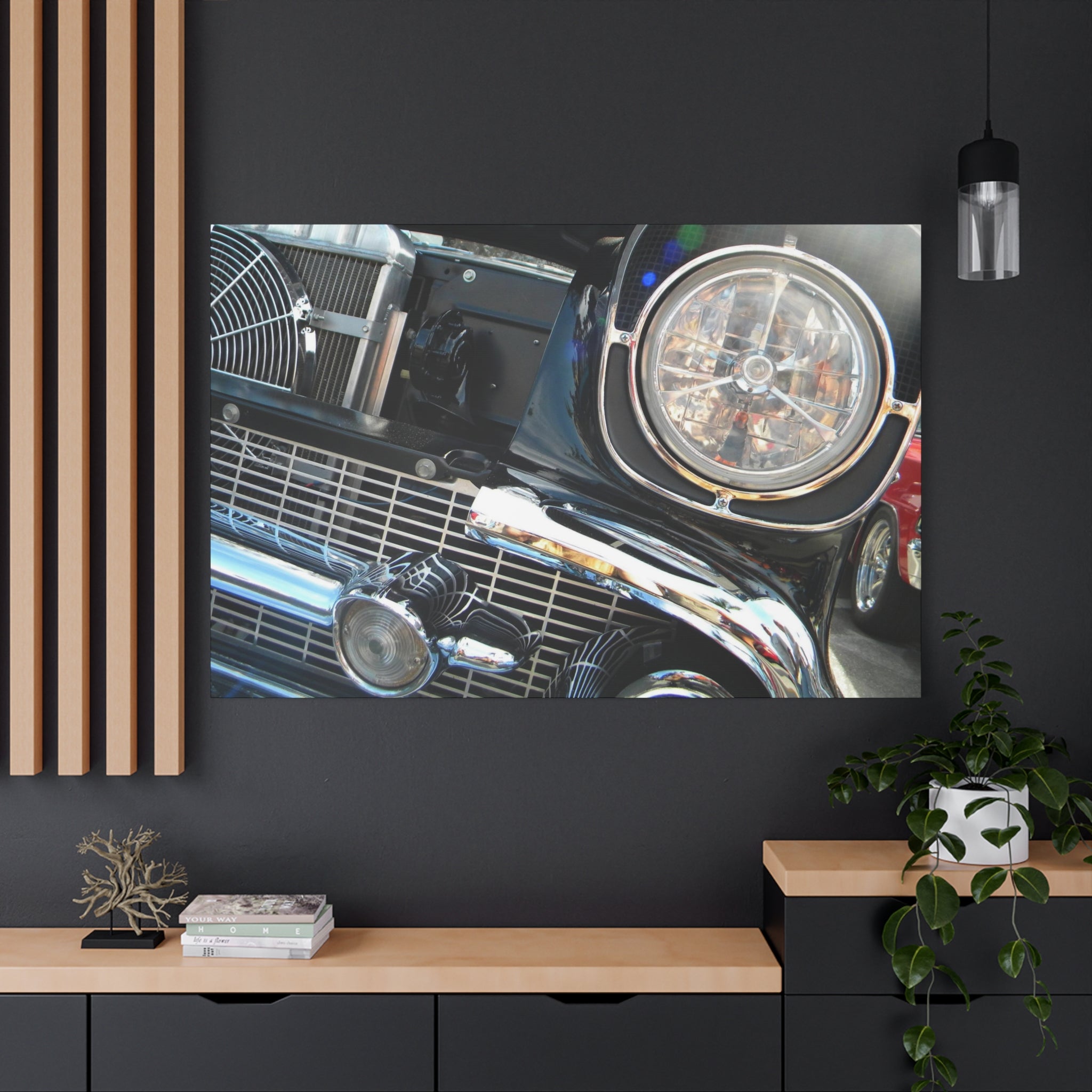 Close-up of a car's headlight and grille on a dark wall with a wooden shelf below.