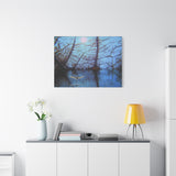 Canvas print of a bird flying over water with tree reflections at dusk.