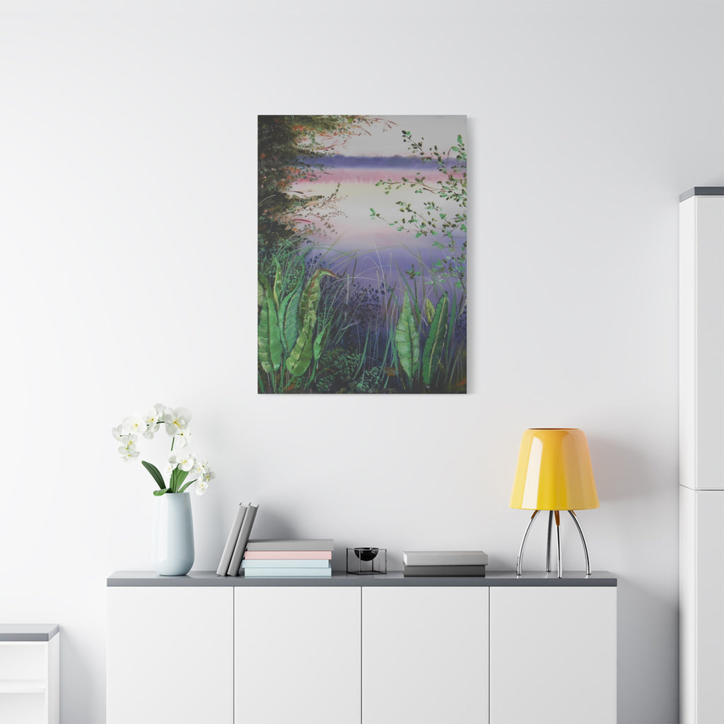 Canvas print of a nature scene hanging on a white wall above a desk with a lamp and books.
