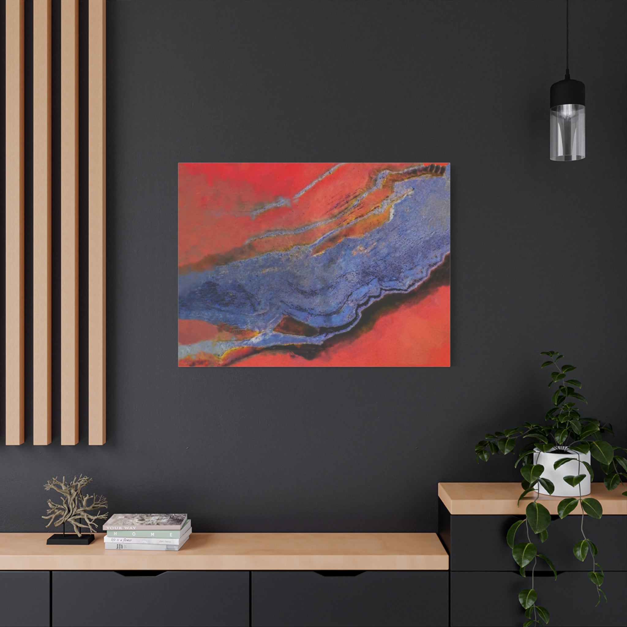 Abstract art piece on a dark wall with a wooden shelf and plant.