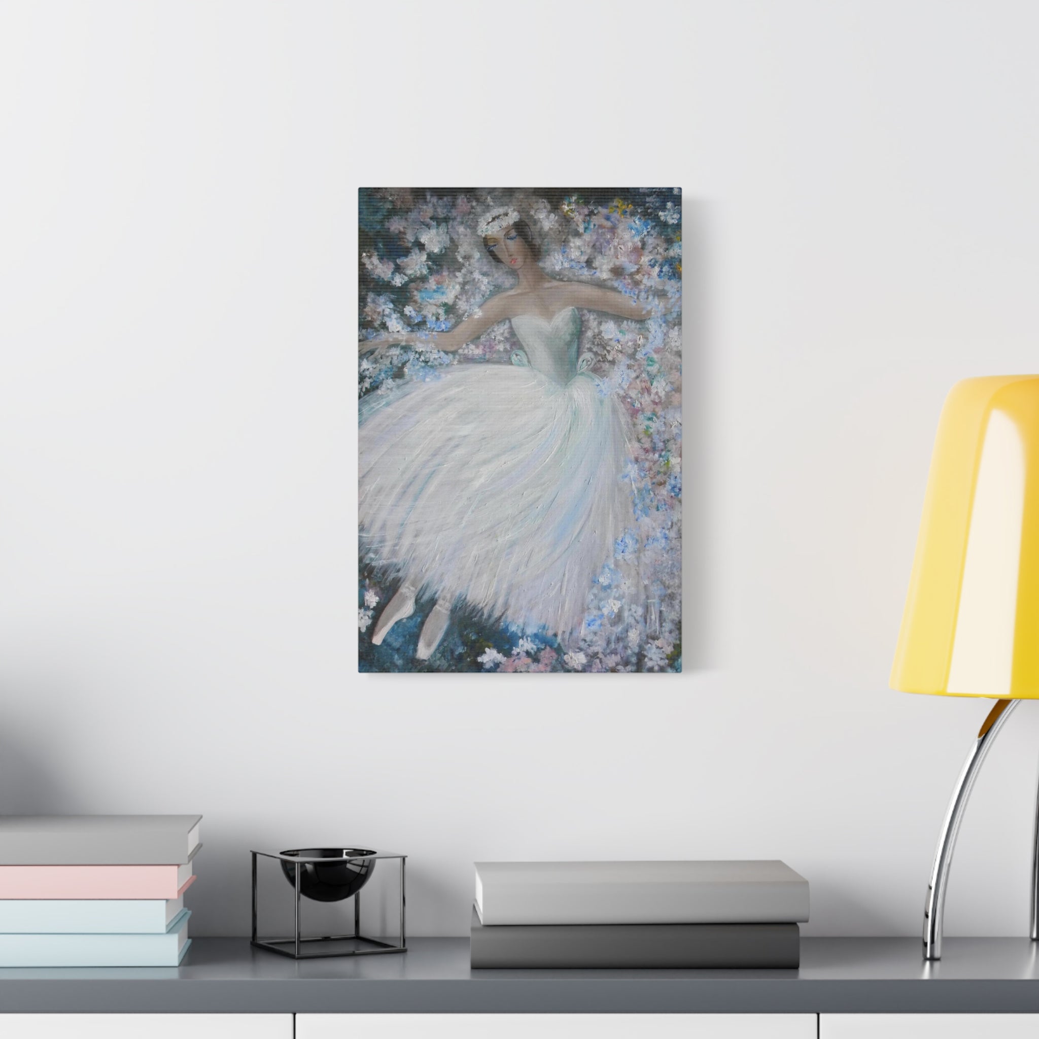 Framed artwork of a dancer in a white dress on a wall above a desk with books and a lamp.